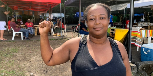 Marylis Colzin, une infirmière protestant contre les vaccinations obligatoires en France pour les personnels de santé, pose à Pointe-à-Pitre, île de Guadeloupe, dimanche 21 novembre 2021. Les autorités françaises envoient des forces spéciales de police sur l'île caribéenne de Guadeloupe, un territoire d'outre-mer de France, alors que les protestations contre les restrictions liées au COVID-19 ont dégénéré en émeutes. À Pointe-à-Pitre, la plus grande zone urbaine de l'île, des affrontements ont fait trois blessés, dont une femme de 80 ans qui a été touchée par une balle alors qu'elle se trouvait sur son balcon. (AP Photo/Elodie Soupama)
