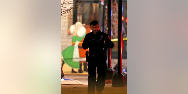 Holiday decorations frame a police officer as he walks in downtown Waukesha, Wis., after a vehicle plowed into a Christmas parade injuring multiple people Sunday, Nov. 21, 2021.