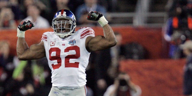 In this Feb. 3, 2008 file photo, New York Giants defensive end Michael Strahan (92) reacts after sacking New England Patriots quarterback Tom Brady (12) in the third quarter of the Super Bowl XLII football game at University of Phoenix Stadium in Glendale, Ariz. Strahan is looking forward to seeing his No. 92 jersey retired by the Giants, and wondering why it took so long. The never-shy Strahan on Wednesday, Nov. 24, 2021 took a swipe at the team's ownership for lateness of his jersey retirement, nipped at fans of the rival Philadelphia Eagles and added he is as frustrated as any Giants' fan by the team struggles over the past decade.
