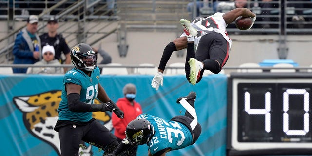 Atlanta Falcons wide receiver Russell Gage leaps over Jacksonville Jaguars cornerback Tyson Campbell and defensive end Dawuane Smoot after a reception Sunday, 十一月. 28, 2021, （杰克逊维尔）, 佛罗里达.