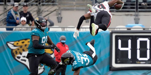 Atlanta Falcons wide receiver Russell Gage leaps over Jacksonville Jaguars cornerback Tyson Campbell and defensive end Dawuane Smoot after a reception Sunday, 十一月. 28, 2021, (杰克逊维尔), 佛罗里达.