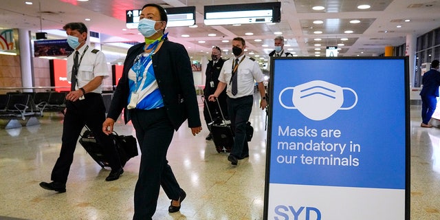 A flight crew walk through the terminal at Sydney Airport, Monday, Nov. 29, 2021. (AP Photo/Mark Baker)
