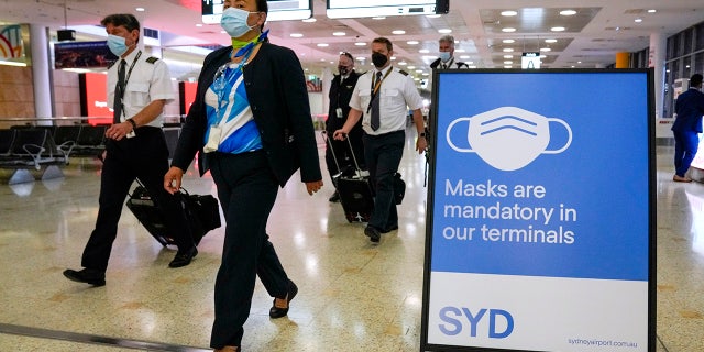 A flight crew walk through the terminal at Sydney Airport, Monday, Nov. 29, 2021. (AP Photo/Mark Baker)