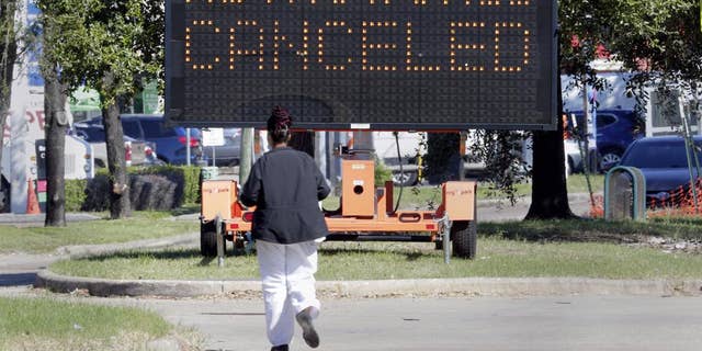 A pedestrian cross Main Street in front of a sign announcing the cancellation of Astroworld on Saturday, Nov. 6, 2021, in Houston. (AP Photo/Michael Wyke)