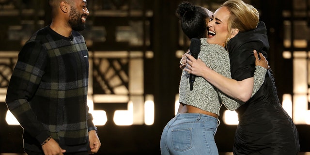Quentin Brunson, left, looks on as his fiancée, Ashleigh Mann, hugs Adele after saying ‘yes'  to his marriage proposal at the Grammy winner's primetime performance. 