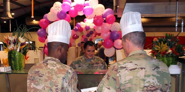 AL DHAFRA AIR BASE, United Arab Emirates - Senior Airman DeMarco Rodriguez joined a group of his fellow Ground Transportation team for a Thanksgiving meal, being served by Chief Master Sgt. Olatokunbo Olopade, command chief for the 380th Air Expeditionary Wing, and Brig. Gen. Andrew Clark, 380th AEW commander, at Al Dhafra Air Base, Nov. 25, 2021. (U.S. Air Force photo by Master Sgt. Dan Heaton) 