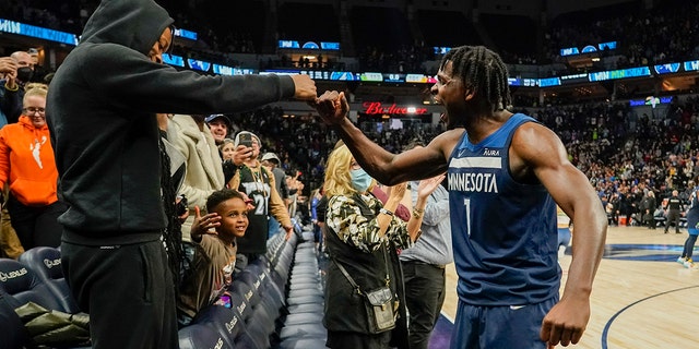 Minnesota Timberwolves guard Anthony Edwards celebrates with a fan after defeating the Miami Heat 113-101 during an NBA basketball game Wednesday, Nov. 24, 2021, in Minneapolis. Edwards scored 33 points in the game. 