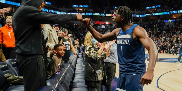 Minnesota Timberwolves guard Anthony Edwards celebrates with a fan after defeating the Miami Heat 113-101 during an NBA basketball game Wednesday, Nov. 24, 2021, in Minneapolis. Edwards scored 33 points in the game. 