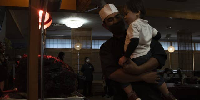 NAVAL AIR FACILITY ATSUGI, Japan - Culinary Specialist 1st Class Frederick Cristobal shows a family member a carving station during a Thanksgiving meal served at the Naval Air Facility (NAF) Atsugi base Far East Cafe galley on Nov. 25, 2021. (U.S. Navy photo by Mass Communication Specialist 1st Class Richard L.J. Gourley)