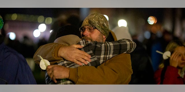 People hold candles and embrace during a vigil in Cutler Park on Monday in Waukesha, Wisconsin