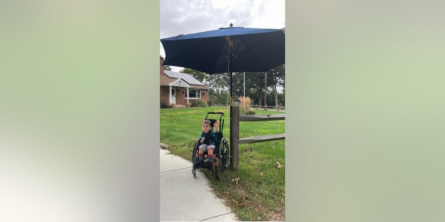 Ryder Killam waiting for the bus with his makeshift umbrella bus stop. 