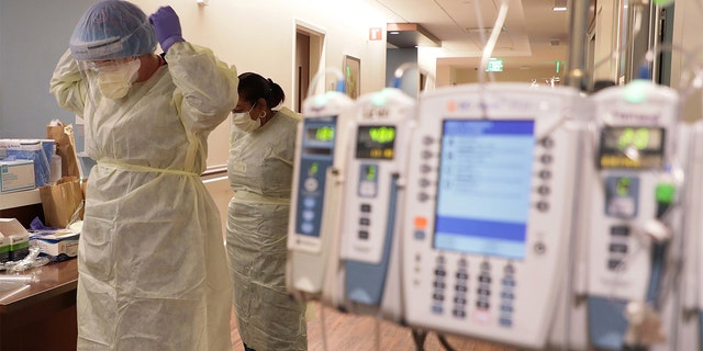 ICU nurse Samantha Lazzara, left, and Judith Mclean, right, a patient care technician, put on PPE gear before entering a COVID-19 patient's room in the ICU unit at Northwestern Medicine Lake Forest Hospital on Friday, Oct. 1, 2021, in Lake Forest, Illinois. 