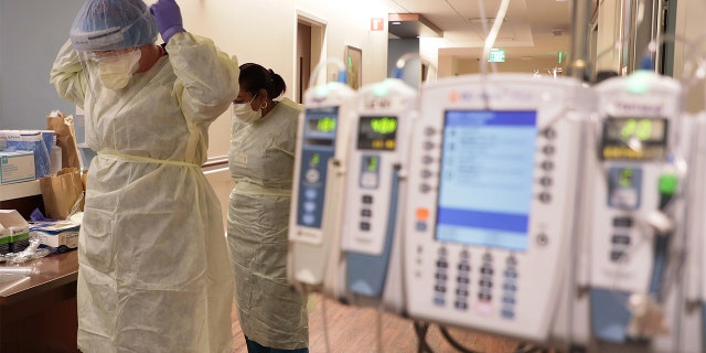 ICU nurse Samantha Lazzara, left, and Judith Mclean, right, a patient care technician, put on PPE gear before entering a COVID-19 patient's room in the ICU unit at Northwestern Medicine Lake Forest Hospital on Friday, Oct. 1, 2021, in Lake Forest, Illinois.