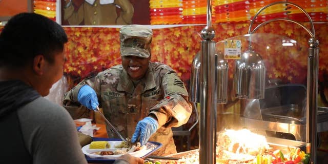 El mando del sargento.  La mayor Veronica Harvey, asesora sénior alistada en la División de Operaciones de Apoyo de la Tercera Brigada de Sostenimiento, coloca algunos trozos de pavo en el plato de un soldado del Ejército de los EE. UU. En un comedor en Camp Arifjan, en Kuwait, el 25 de noviembre.  Los equipos de mando de Camp Arifijan sirven a los soldados el día de Acción de Gracias para mostrar su agradecimiento durante las vacaciones.  (Fotografía del ejército de los EE. UU. Por el sargento Marquis Hopkins) 