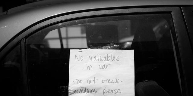 San Francisco'da park halindeki bir arabadaki bir tabela, camların kırılmamasını istiyor ve içeride değerli eşya olmadığını bildiriyor.