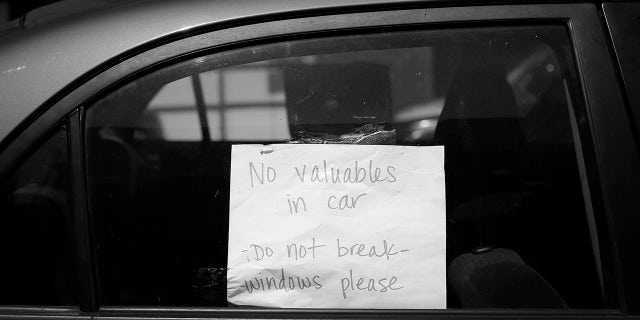 A sign in a parked car in San Francisco asks for the windows not to be broken and informs that there are no valuables inside.