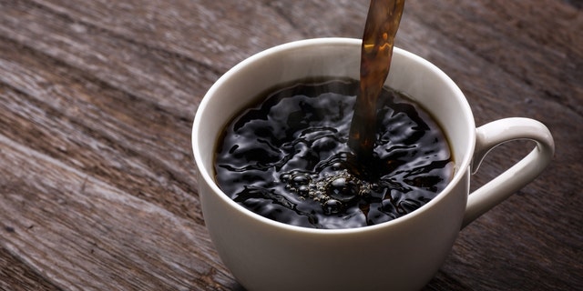 Black coffee pours into a white mug.