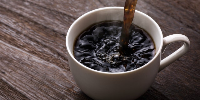 O café preto é derramado em uma caneca branca.
