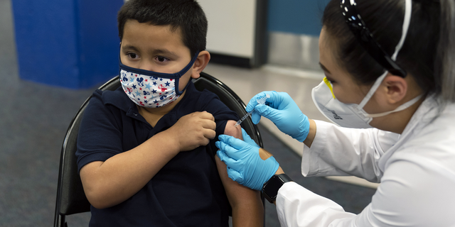Eric Aviles, 6, ontvangt het Pfizer COVID-19-vaccin van apotheker Sylvia Uong in een pediatrische vaccinkliniek voor kinderen van 5 tot 11 jaar die is opgezet op de Willard Intermediate School in Santa Ana, Californië, op 9 november.