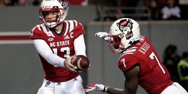 North Carolina State quarterback Devin Leary (13) hands off to running back Zonovan Knight (7) during the first half of the team's NCAA college football game against North Carolina on Friday, Nov. 26, 2021, in Raleigh, Carolina del Nord.
