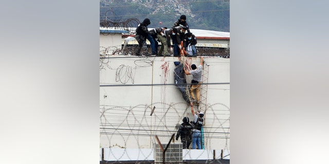 Police lower the body of a prisoner from the roof of the Litoral penitentiary the morning after riots broke out inside the jail in Guayaquil, Ecuador, Saturday, Nov. 13, 2021.