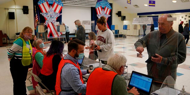 Voters wait in line to check in to vote at a school in Midlothian, Va., Tuesday, Nov. 2, 2021. Voters are deciding between Democrat Terry McAuliffe and Republican Glenn Youngkin for Governor. (AP Photo/Steve Helber)