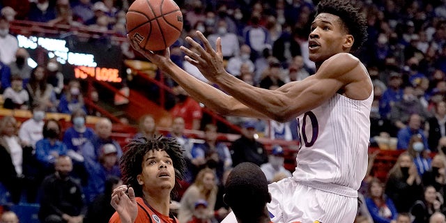 Kansas's Ochai Agbaji shoots over Stony Brook's Elijah Olaniyi and Frankie Policelli, right, during the first half of an NCAA college basketball game Thursday, Nov. 18, 2021, in Lawrence, Kan.