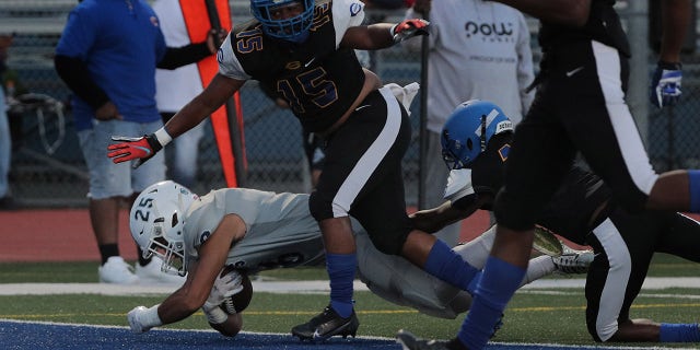 Reseda running back Androw Nesem (25) scores against Crenshaw defensive back James Logan (15) to give Reseda the lead in the first half at Crenshaw High School on April 9, 2021 in Los Angeles, California.(Gina Ferazzi / Los Angeles Times via Getty Images)