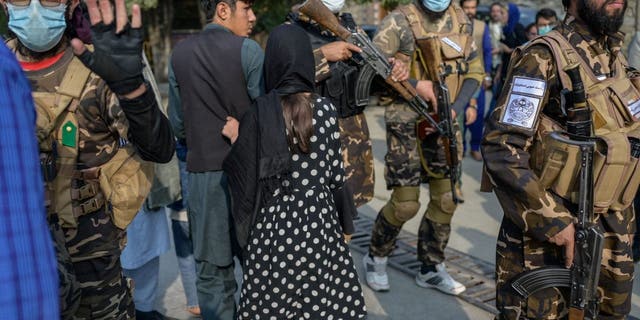 A Taliban fighter (left) makes a hand gesture asking the photojournalists to stop covering a demonstration by women protesters in Kabul, Afghanistan, on Sept. 30, 2021. 