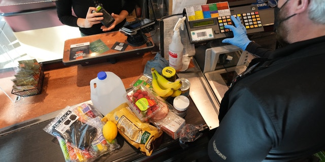 A cashier assists a customer at a checkout counter at Harmons Grocery store in Salt Lake City, 유타, 목요일에, 10 월. 21, 2021. More than a year and a half after the coronavirus pandemic upended daily life, the supply of basic goods at U.S. grocery stores and restaurants is once again falling victim to intermittent shortages and delays. 
