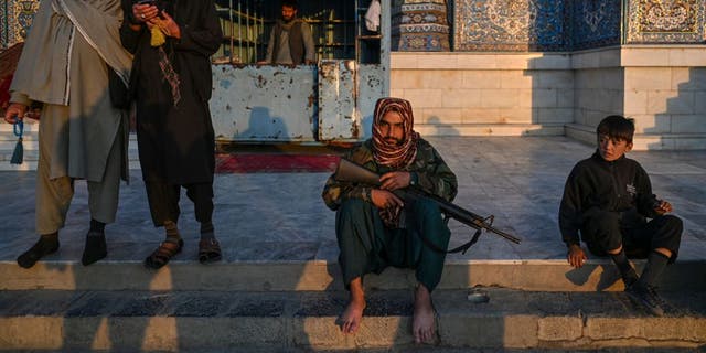 A Taliban fighter sits in front of the Sakhi Shrine in the Karte Sakhi area of Kabul on Nov. 1, 2021. (Photo by Hector RETAMAL / AFP)