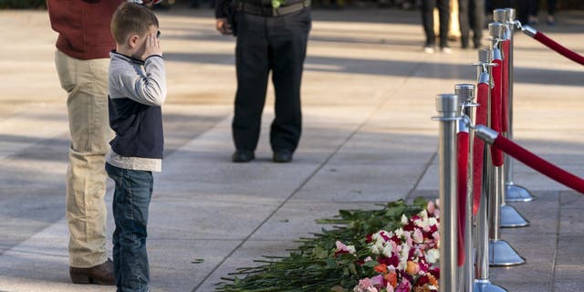 A young boy salutes after placing a flower during a commemorative event at the Tomb of the Unknown Soldier in Arlington National Cemetery in Arlington, Virginia. 