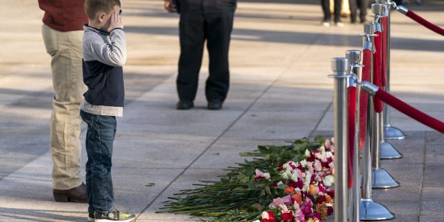 A young boy salutes after placing a flower during a commemorative event at the Tomb of the Unknown Soldier in Arlington National Cemetery in Arlington, Virginia.