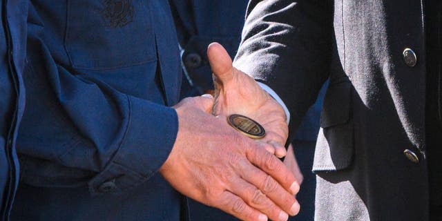 President Biden hands a service member a challenge coin as he greets members of the Coast Guard at U.S. Coast Guard Station Brant Point in Nantucket, Massachusetts, on Nov. 25, 2021. Biden is in Nantucket to spend the Thanksgiving holiday. (Photo by MANDEL NGAN/AFP via Getty Images)