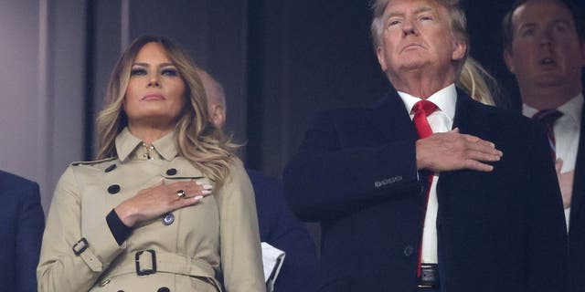 ATLANTA, GEORGIA - OCTOBER 30:  Former first lady and president of the United States Melania and Donald Trump stand for the national anthem prior to Game Four of the World Series between the Houston Astros and the Atlanta Braves Truist Park on October 30, 2021 in Atlanta, Georgia. (Photo by Elsa/Getty Images)