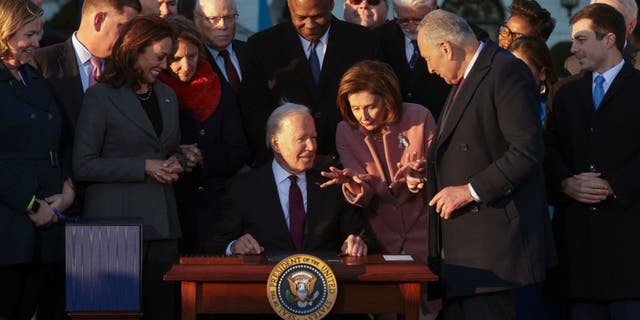 WASHINGTON, DC - NOVEMBER 15: U.S. President Joe Biden talks to Speaker of the House Nancy Pelosi after signing the Infrastructure Investment and Jobs Act as he is surrounded by lawmakers and members of his Cabinet during a ceremony on the South Lawn at the White House on November 15, 2021 in Washington, DC. The $1.2 trillion package will provide funds for public infrastructure projects including improvements to the country’s transportation networks, increasing rural broadband access, and projects to modernizing water and energy systems. (Photo by Alex Wong/Getty Images)