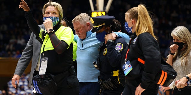 DURHAM, NORTH CAROLINA - NOVEMBER 22: Head coach Duggar Baucom of the Citadel Bulldogs is helped off of the floor after a medical incident during the first half of their game against the Duke Blue Devils at Cameron Indoor Stadium on November 22, 2021 in Durham, North Carolina.