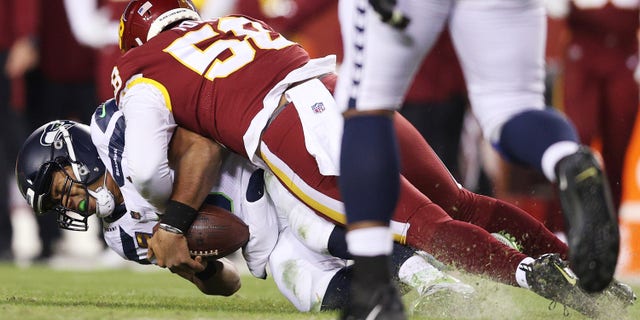 LANDOVER, MARYLAND - NOVEMBER 29: Shaka Toney #58 of the Washington Football Team tackles Russell Wilson #3 of the Seattle Seahawks during the fourth quarter at FedExField on November 29, 2021 in Landover, Maryland. 