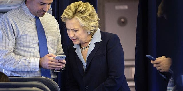 Democratic presidential nominee Hillary Clinton looks at a smart phone with national press secretary Brian Fallon on  her plane at Westchester County Airport October 3, 2016. (BRENDAN SMIALOWSKI/AFP via Getty Images)