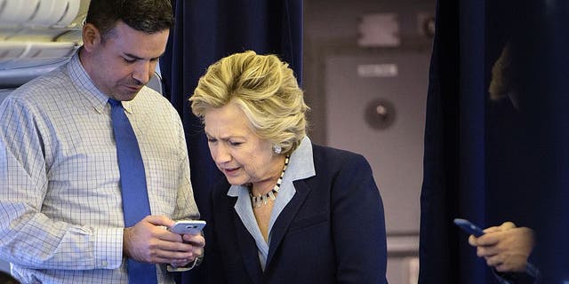 Democratic presidential nominee Hillary Clinton looks at a smart phone with national press secretary Brian Fallon on her plane at Westchester County Airport October 3, 2016. (BRENDAN SMIALOWSKI/AFP via Getty Images)