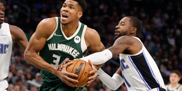 Milwaukee Bucks forward Giannis Antetokounmpo (34) is fouled by Orlando Magic guard Terrence Ross, right, during the first half of an NBA basketball game Monday, Nov. 22, 2021, in Milwaukee.