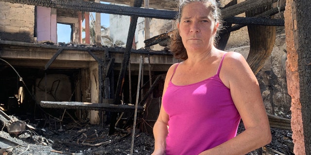 Emilie holds her burned passport in her charred home following riots in Pointe-a-Pitre, Guadeloupe island, on Sunday, Nov. 21, 2021.Â