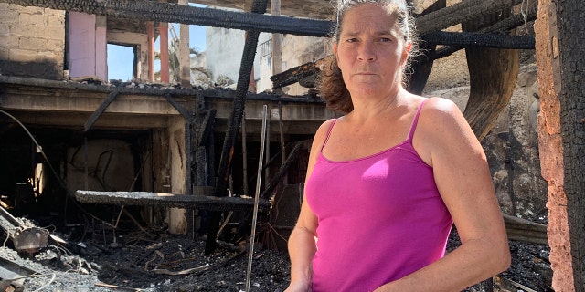 Emilie holds her burned passport in her charred home following riots in Pointe-a-Pitre, Guadeloupe island, on Sunday, Nov. 21, 2021. 