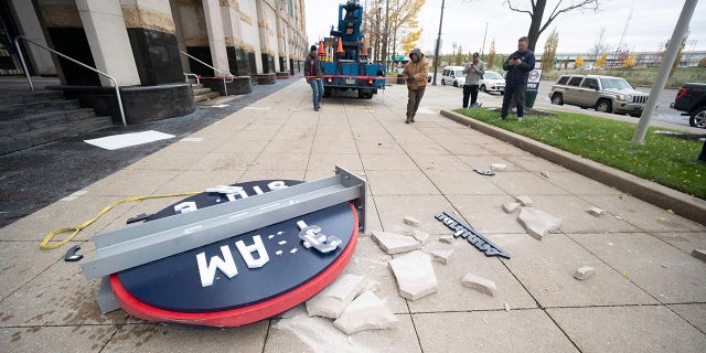 Workers from the Brilliant Electric Sign Company put out caution tape after pieces of the Cleveland Guardians team store sign fell to the ground in Cleveland, Friday, Nov. 19, 2021. The sign was being installed and fell off the building.