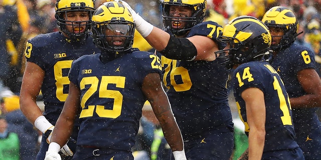 ANN ARBOR, 密歇根州 - 十一月 27: Hassan Haskins #25 of the Michigan Wolverines celebrates with teammates after his touchdown against the Ohio State Buckeyes during the second quarter at Michigan Stadium on November 27, 2021 in Ann Arbor, 密西根州.