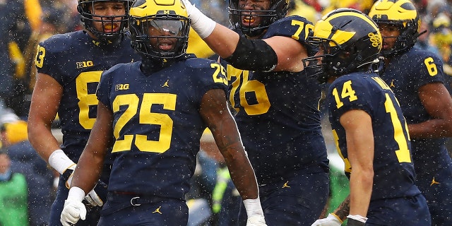 ANN ARBOR, MICHIGAN - 11月 27: Hassan Haskins #25 of the Michigan Wolverines celebrates with teammates after his touchdown against the Ohio State Buckeyes during the second quarter at Michigan Stadium on November 27, 2021 in Ann Arbor, ミシガン.