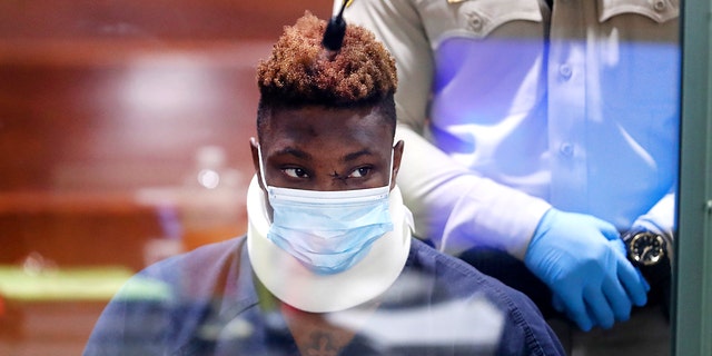 Former Las Vegas Raiders wide receiver Henry Ruggs III makes an initial appearance in Las Vegas Justice Court on Nov. 3, 2021 in Las Vegas, Nevada. Ruggs is facing charges relating to a fiery vehicle crash early Tuesday in Las Vegas that left a woman dead and Ruggs and his female passenger injured. The photo is taken through a glass window.