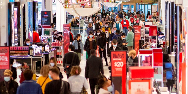 Customers shop at Macys department store in New York on Black Friday, November 27, 2020. - The coronavirus is clouding "Black Friday" much as it has overshadowed 2020 in general, but some leading experts still expect strong overall sales even as shopping patterns are altered.