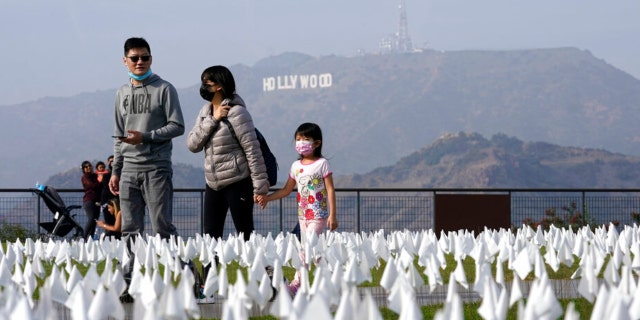 Visitors will pass the COVID-19 Victims Memorial at the Griffith Observatory on Friday, November 19, 2021 in Los Angeles.  Thousands of flags were laid on the lawn in front of the observatory in memory of those who died at COVID-19 in Los Angeles County as of November 2. 