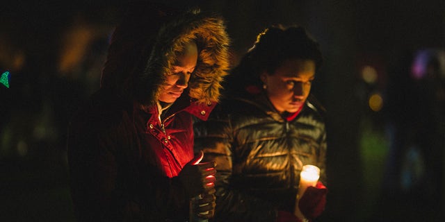 People hold candles during a vigil in Cutler Park on Nov. 22, 2021, in Waukesha, Wisconsin, in honor of those killed and injured during a Christmas parade. 